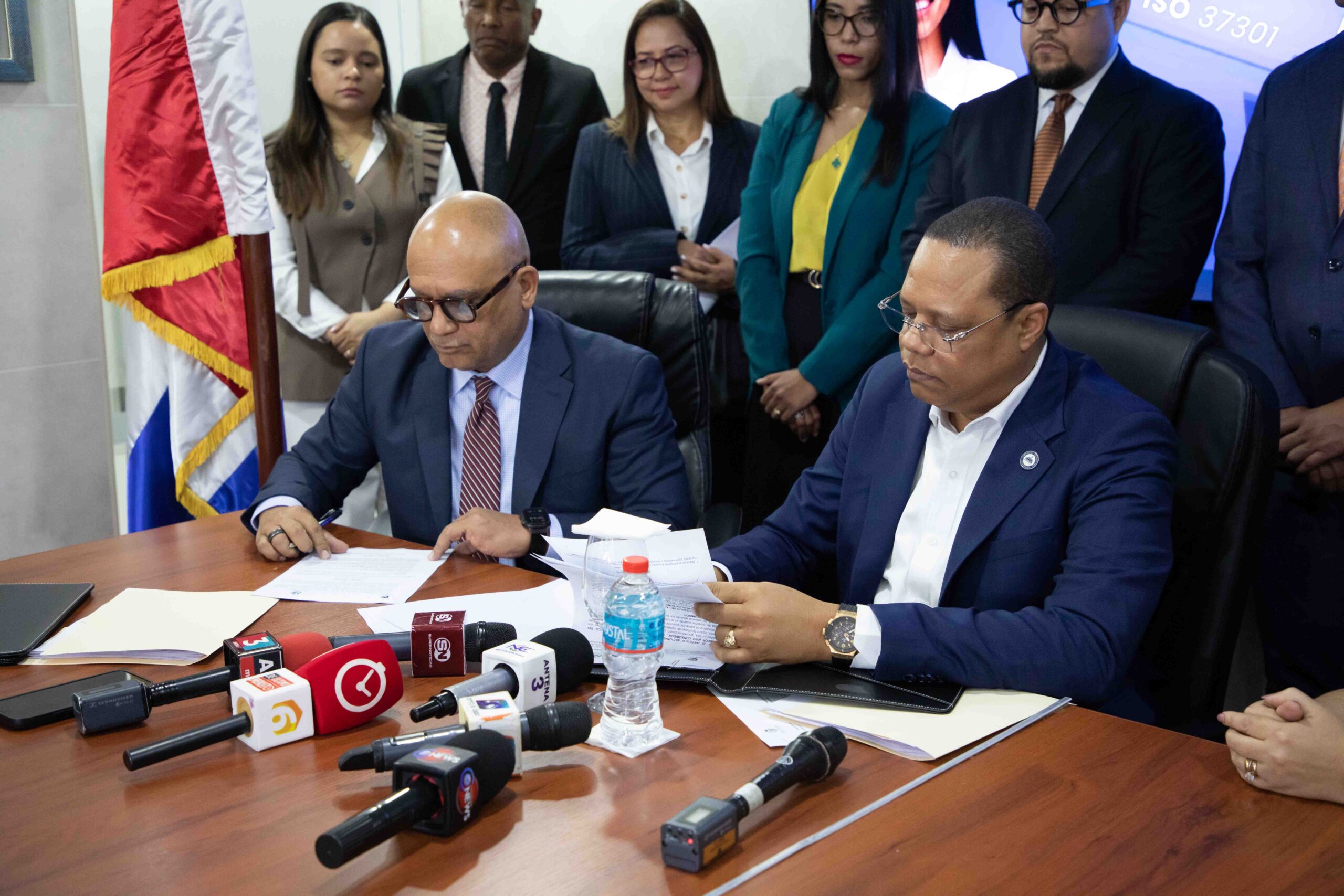 El director ejecutivo de Pro Consumidor, Eddy Alcántara, y representantes de COB-RD firman el acuerdo